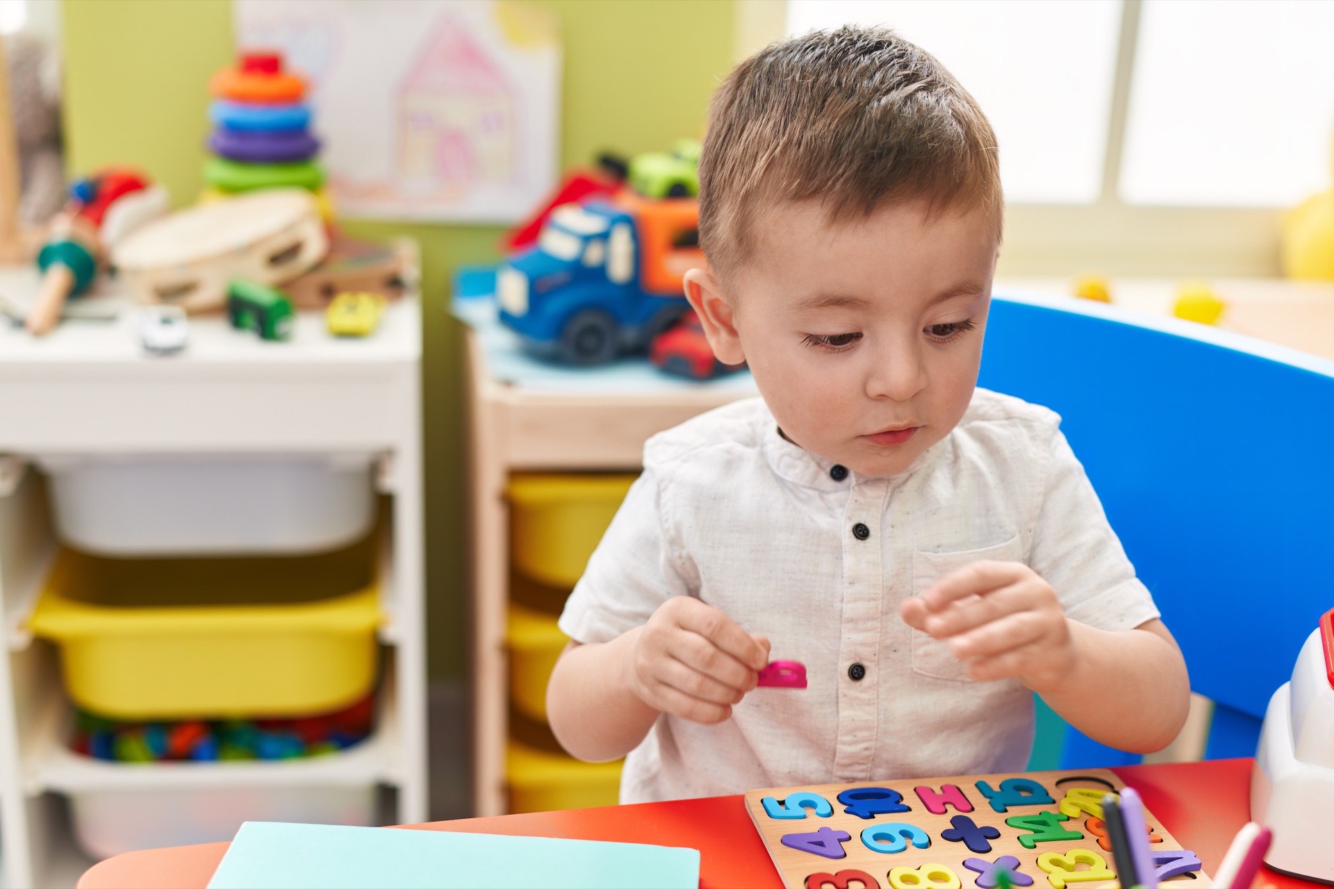 Małe dziecko bawiące się układanką matematyczną przy stoliku w przedszkolu