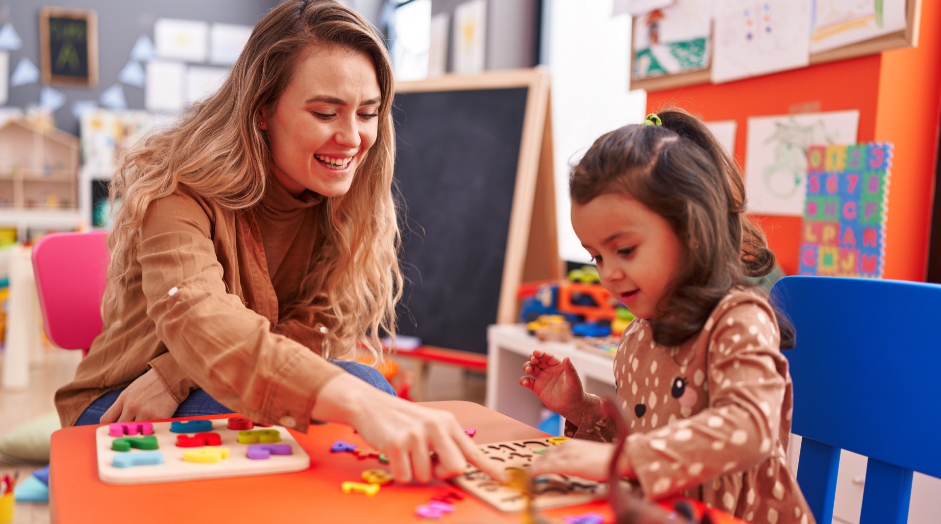 Opiekunka w przedszkolu bawiąca się z dzieckiem przy stoliku edukacyjnym