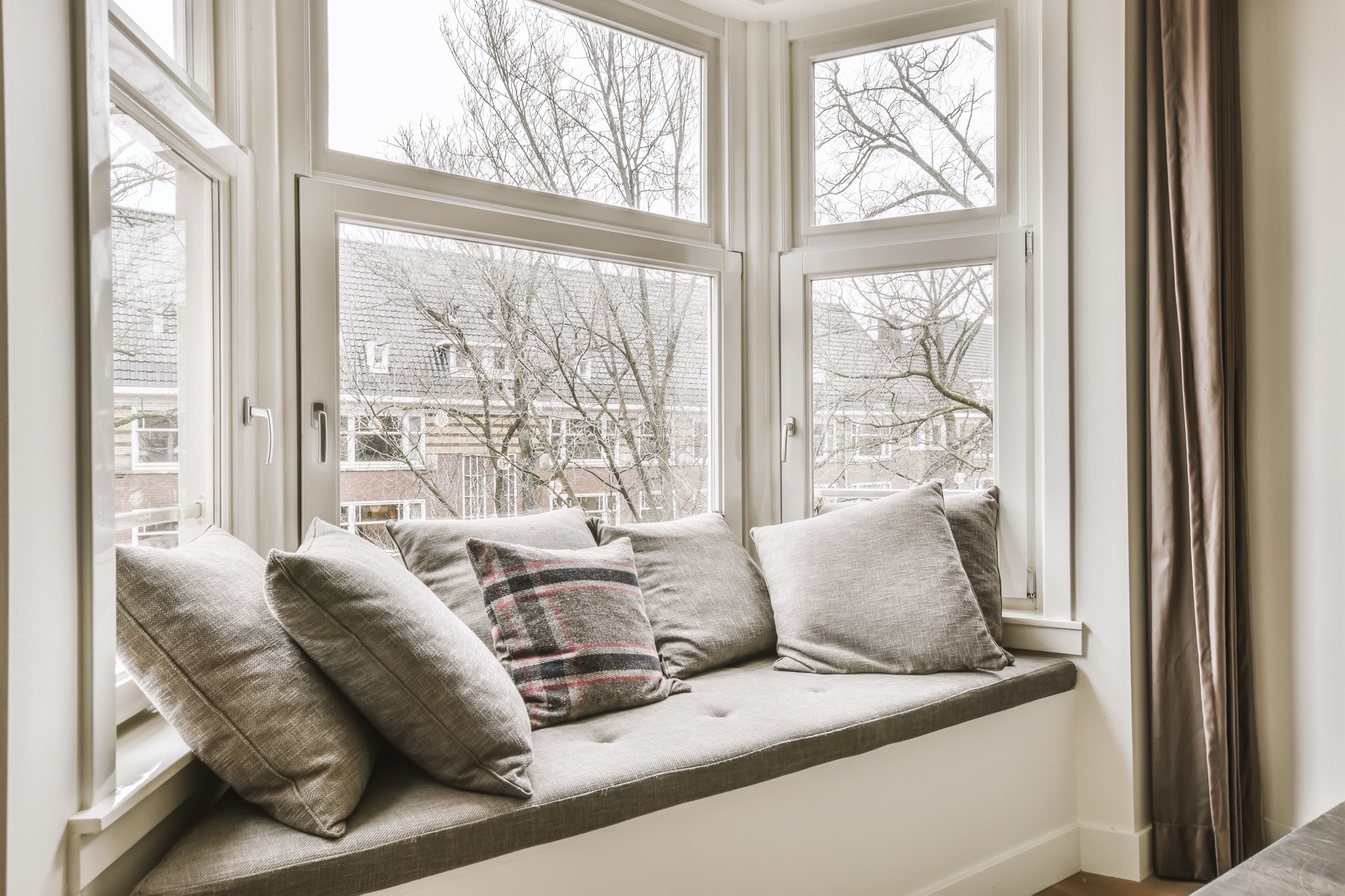 Norweski parapet z poduszkami przy dużym oknie bez zasłon