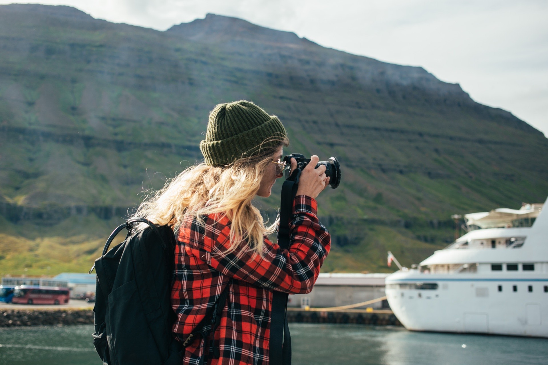 Kobieta fotografuje duży statek wycieczkowy na tle norweskiego fiordu