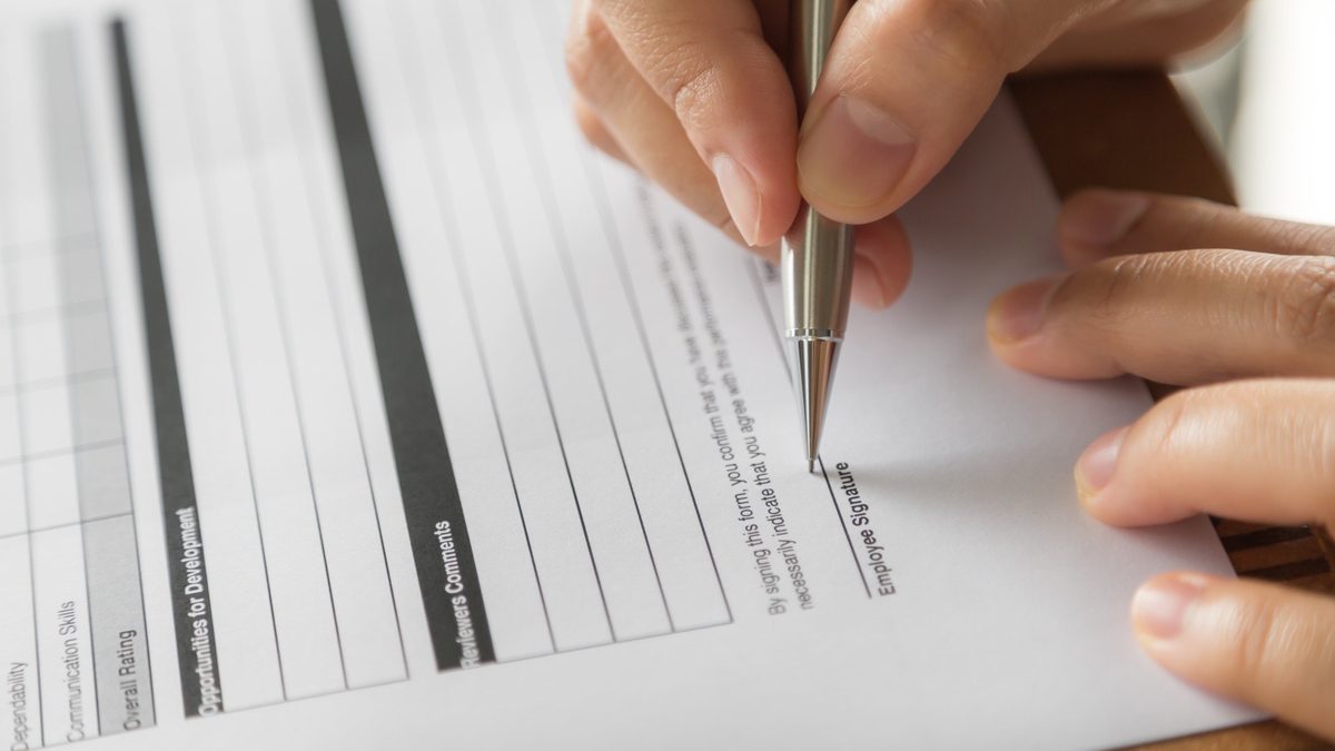 Dłoń z długopisem podpisuje urzędowy formularz