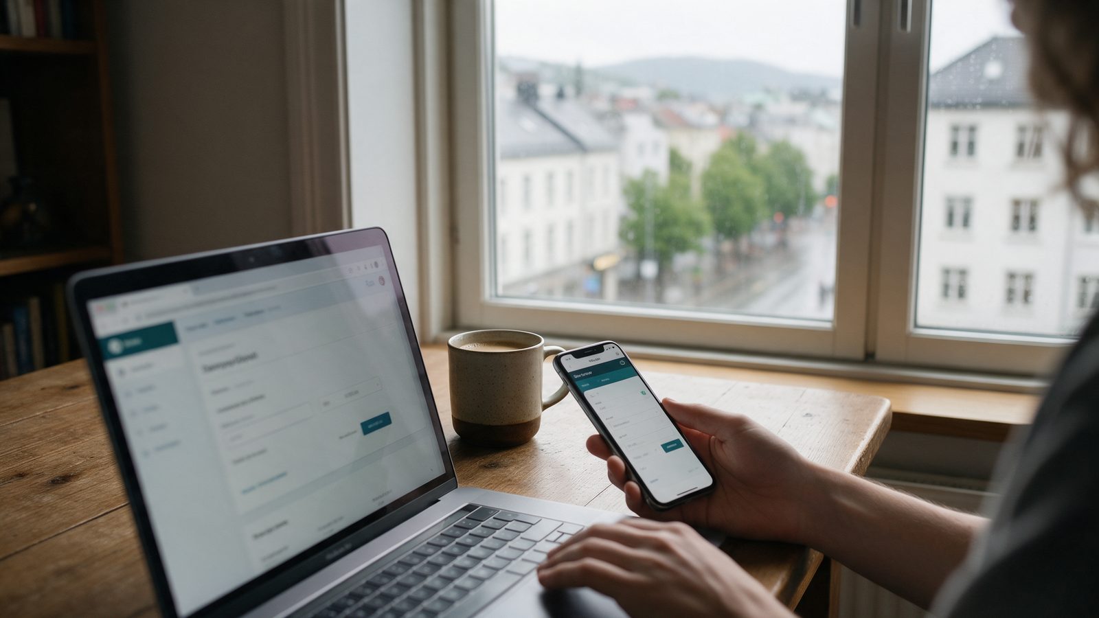 Osoba zakłada konto depozytowe w bankowości internetowej na laptopie i telefonie, za oknem deszczowe miasto