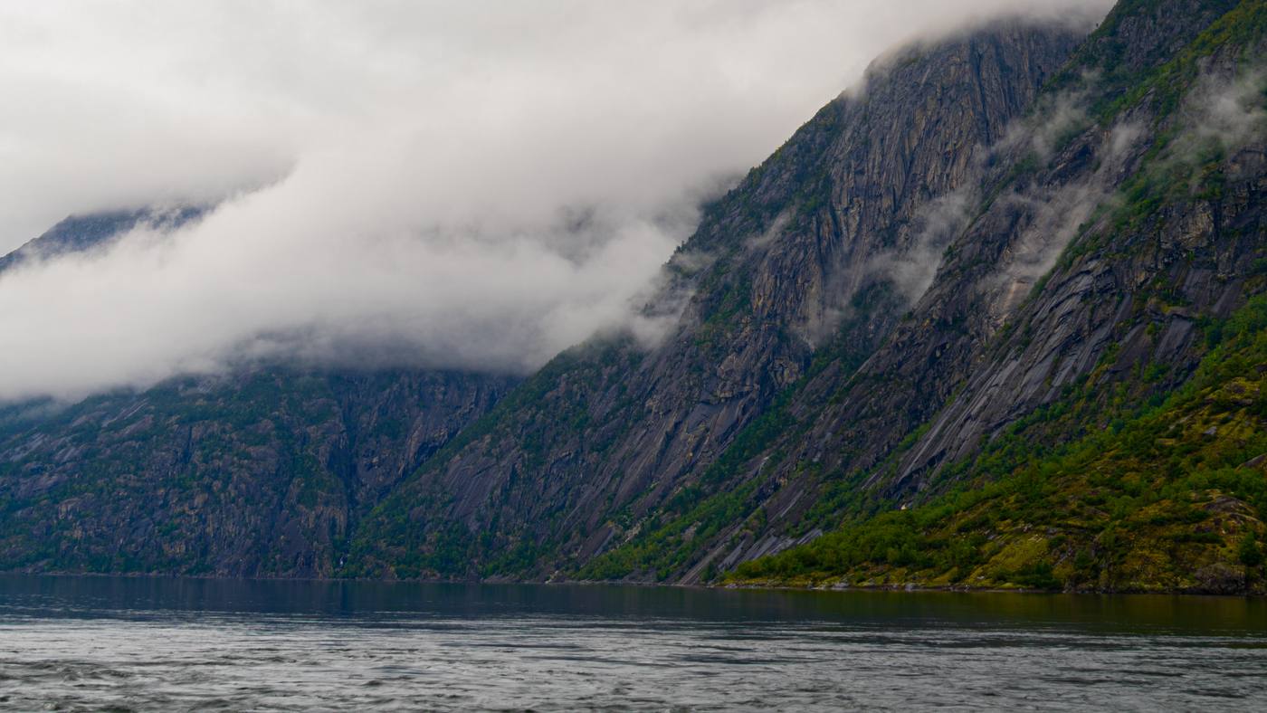 Niskie chmury opadające na zbocza gór nad wodą w Eidfjord