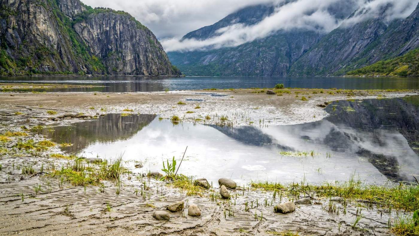 Piaszczyste płycizny Eidfjordvatnet z odbiciem gór i chmur w płytkiej wodzie