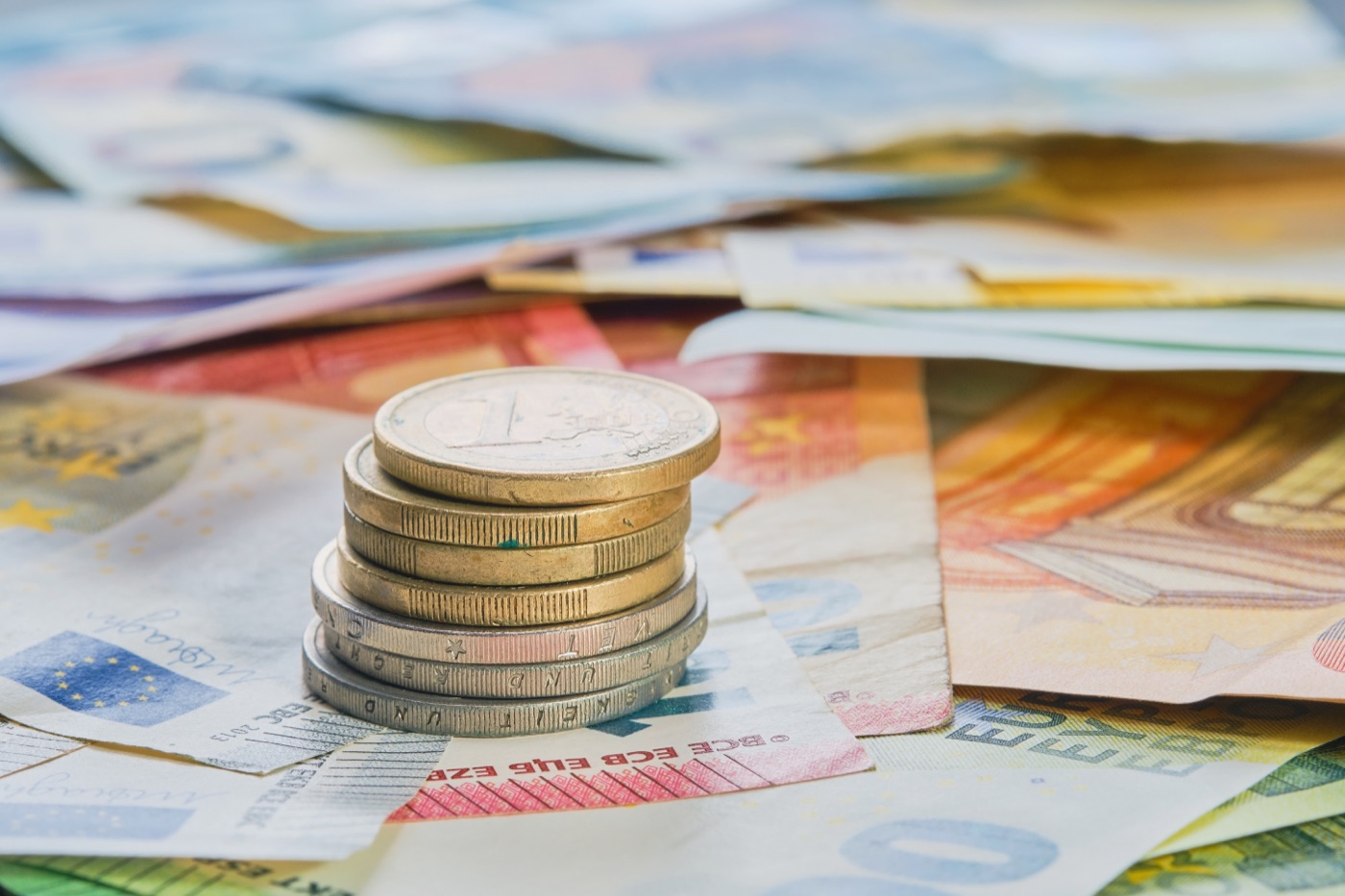 Monety euro ułożone w stos na banknotach – oszczędności