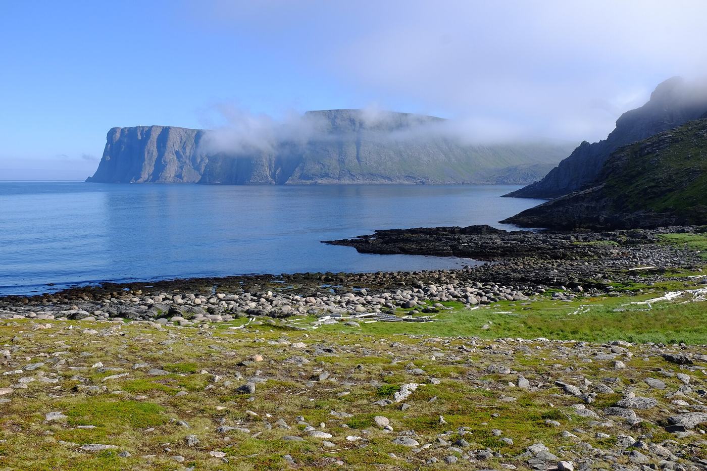 Klif Nordkapp widziany z zatoki Knivskjelvika, mgła nad skałami i spokojne morze