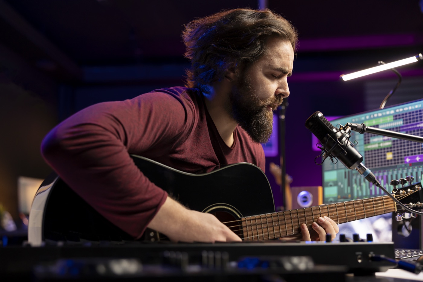 Kompozytor pracujący z gitarą akustyczną w studiu