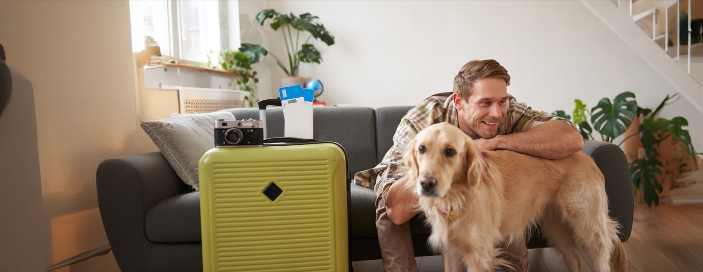 Mężczyzna z psem golden retriever przy walizkach – podróż z psem do Norwegii