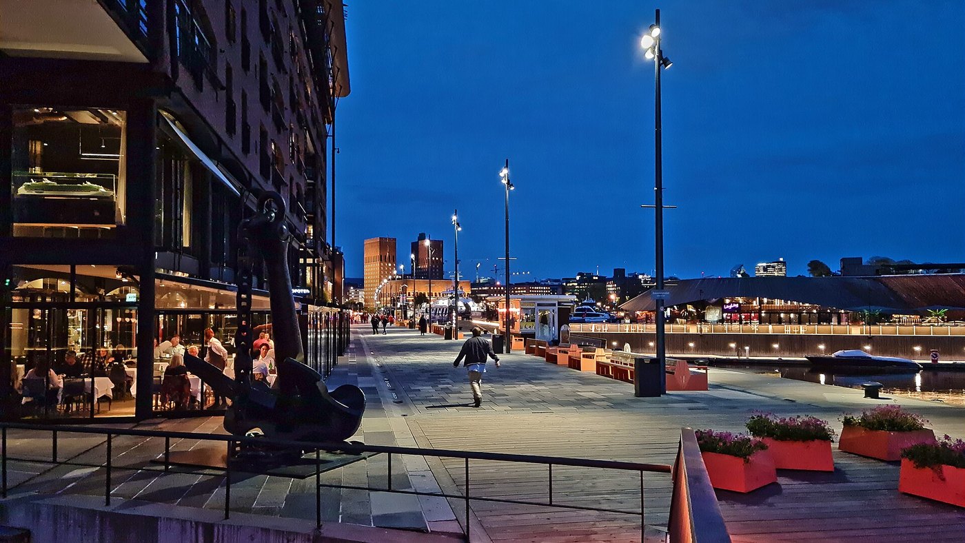 Promenada Aker Brygge w Oslo wieczorem, w tle wieże ratusza